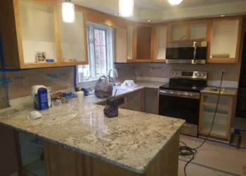 Kitchen cabinets removed of doors and drawers showing preparation stage of cabinet refinishing in Pelham NH