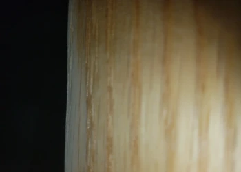 Close-up view of a smooth wood cabinet edge highlighting grain texture during cabinet refinishing in Pelham, NH