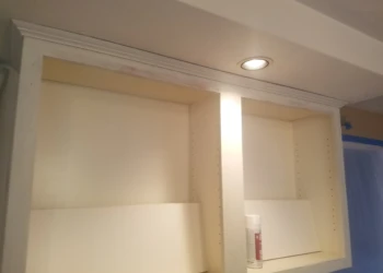 Empty kitchen cabinet frame being refinished in Pelham, NH with fresh paint and recessed lighting above