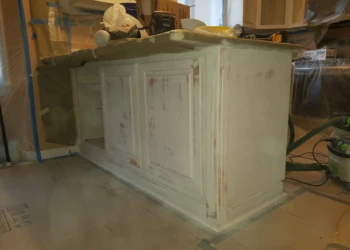 Priming stage of kitchen island cabinets with patching spots during cabinet refinishing in Pelham NH