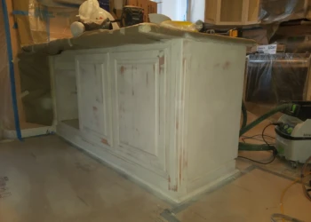 Wood kitchen island cabinets undergoing priming stage with protective coverings and tools in Pelham NH