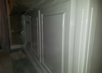 Close-up of freshly painted white kitchen cabinet doors during the cabinet refinishing process in Pelham, NH