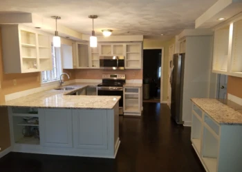 Kitchen with refinished white cabinets and granite countertops in Pelham, NH ready for final hardware installation
