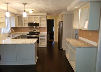 Refinished white kitchen cabinets with granite countertops and stainless steel appliances in a Pelham NH kitchen