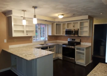 Partially refinished white kitchen cabinets with granite countertops and stainless steel stove in a Pelham NH kitchen