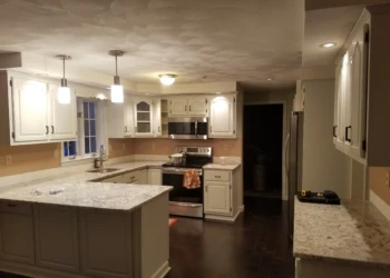 Kitchen with freshly refinished white cabinets, granite countertops, steel appliances, and pendant lighting in Pelham, NH