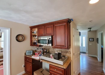 Cherry wood kitchen cabinets with rich finish and decorative crown molding above countertop in Windham, NH home