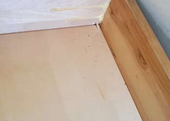 Close-up of a wooden kitchen cabinet drawer bottom corner with glue applied during repair in Windham, NH