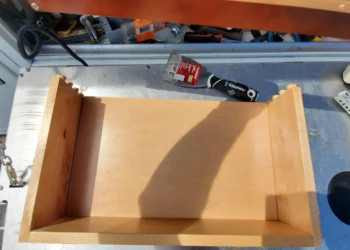 Top view of repaired wooden kitchen drawer on a workbench with tools nearby, part of cabinet painting in Windham NH