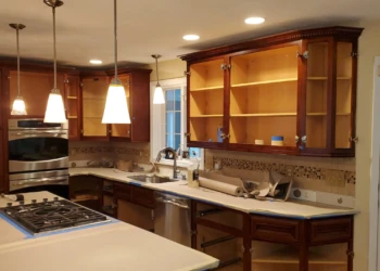 Partially refinished kitchen cabinets with doors off, wood interiors visible, in Windham, NH kitchen mid-project