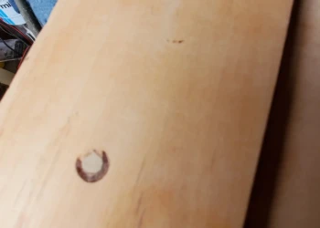 Close-up view of bare wood cabinet drawer with wood splices and repairs visible, during cabinet painting in Windham NH