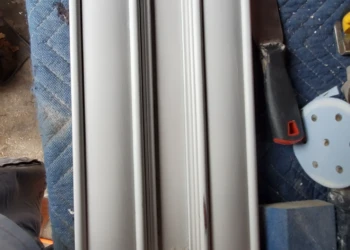 Kitchen cabinet door with minor wood repairs resting on a padded surface with sanding tools nearby for cabinet painting in Windham, NH