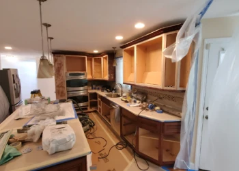 Kitchen cabinets stripped down to bare wood with some drawers removed and protected counters in a Windham, NH home