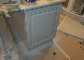 Gray painted kitchen cabinet corner with detailed trim under countertop in a Windham, NH kitchen