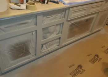 Unfinished kitchen cabinets with surfaces masked and protected for cabinet painting in Windham, NH