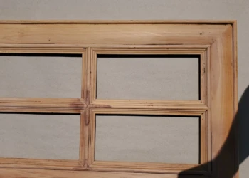 Close-up of a stripped wooden cabinet door frame with natural bare wood exposed before repainting