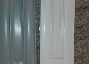 Two kitchen cabinet doors with smooth painted finishes in gray and white on a granite surface, demonstrating cabinet painting in Windham, NH
