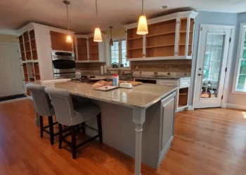 Kitchen showing stripped wooden cabinets and island with granite countertop in Windham NH