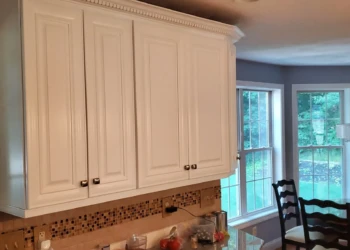 White kitchen cabinets above a tiled backsplash and granite countertop in a Windham, NH home dining area