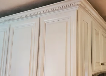 Close-up of freshly refinished white kitchen cabinets with decorative molding in Windham, NH kitchen